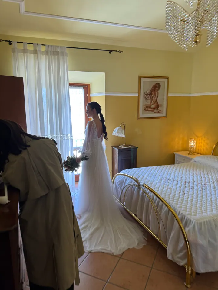 Sposa in abito bianco accanto alla finestra durante la preparazione